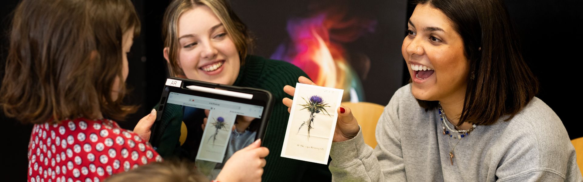 a young girl looks at a picture of a flower through an ipad screen