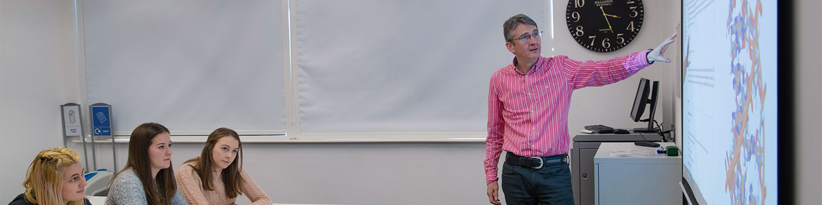 A lecturer stands in front of a white board