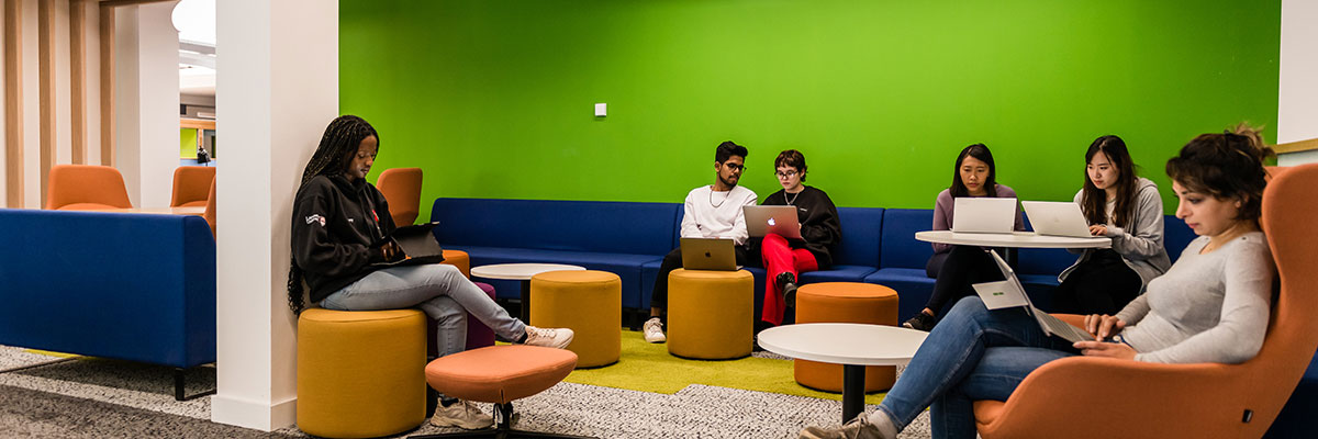 Students studying in an informal space, a mixture of desks and comfortable chairs.