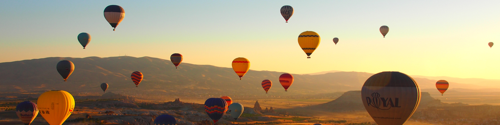 Colourful hot air balloons rising over a rugged southwest american landscape in the sunset