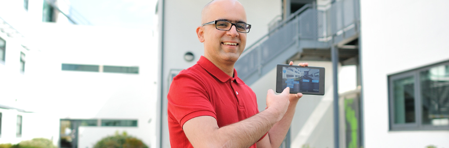 Tarun SaInani holding up a mobile phone displaying the app he created