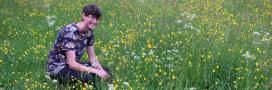 A student sitting in a flowering meadow