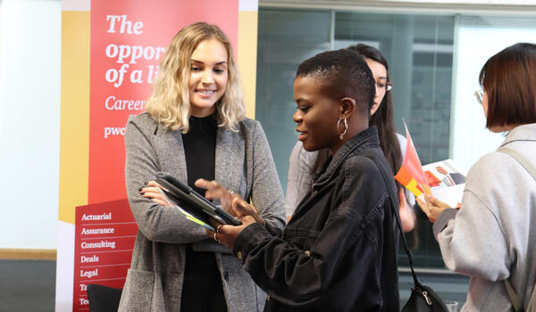 A woman speaking with an employer representative at a careers fair stall