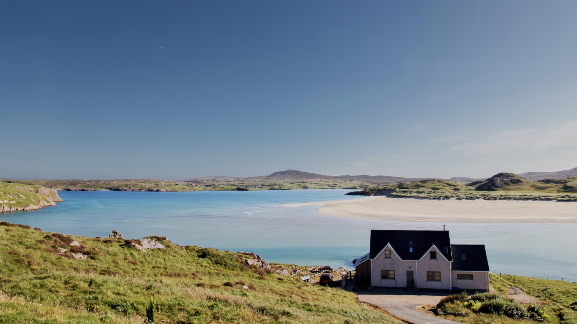 A lone cottage overlooking a sandy bay on the Isle of Lewis