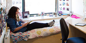 A student sitting on a bed reading