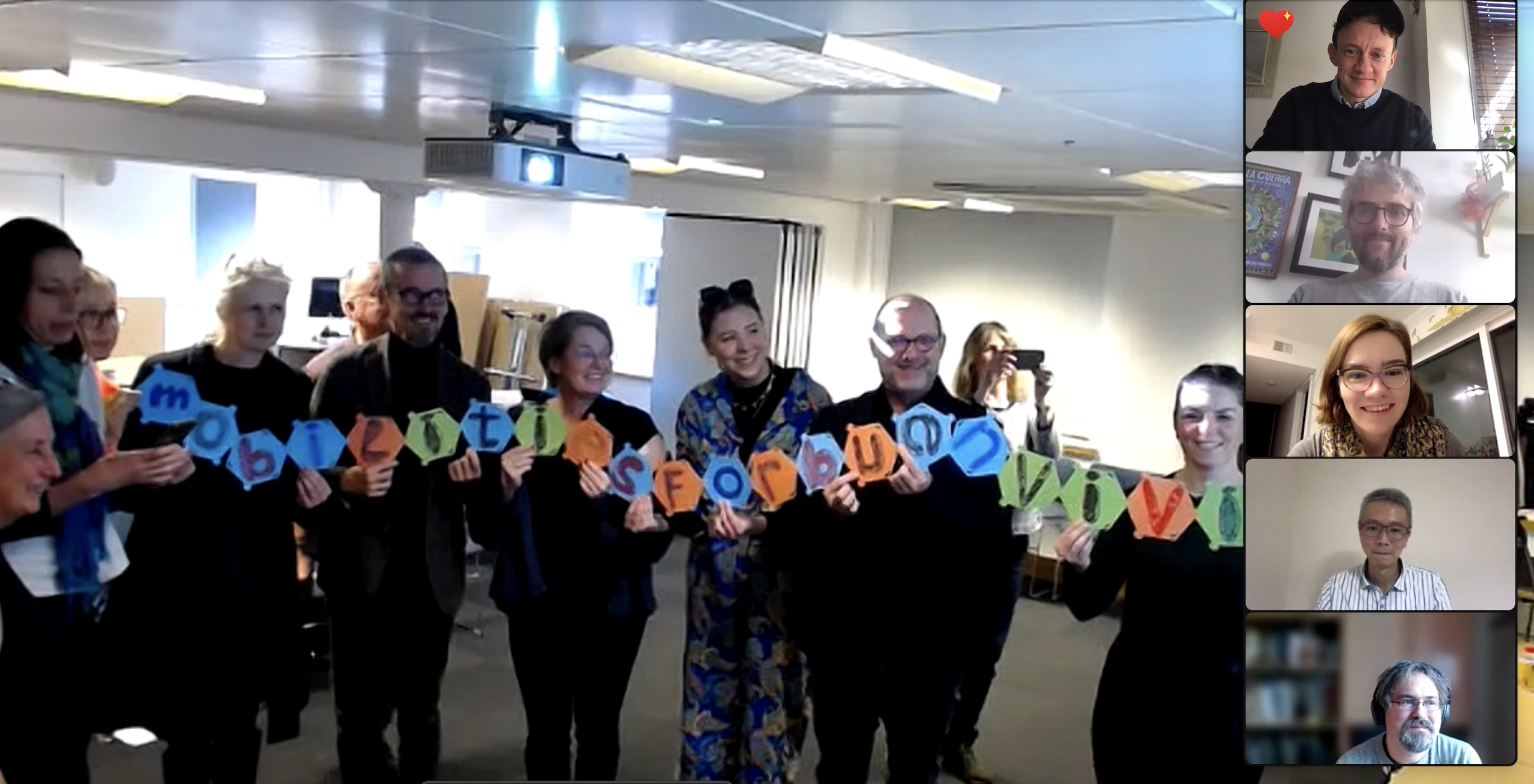 Monika_retirement_screenshot People standing in a row holding up cards that spell 'Mobilities for Beun Vivir'