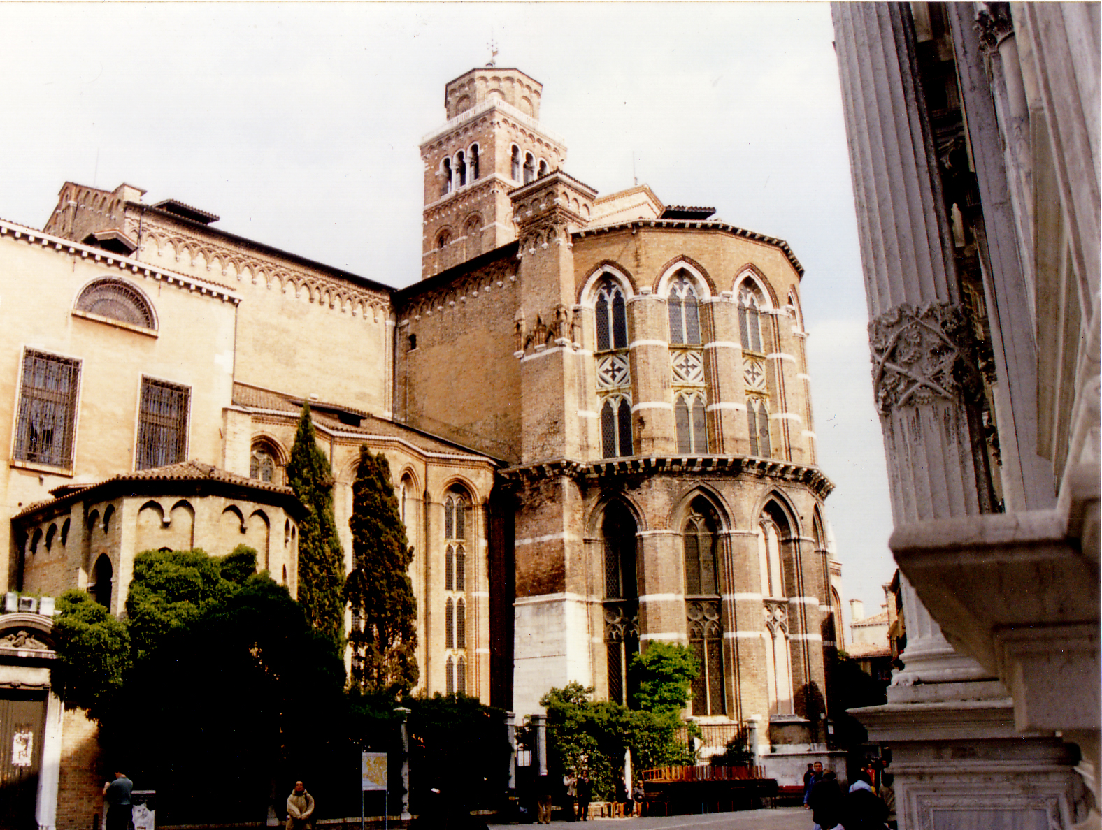 Apse of the church of the Frari to the left, and base and fluted column of the Scuola di San Rocco to the right