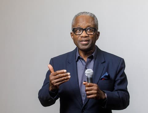 A picture of Renwick Brutus giving a talk holding a microphone