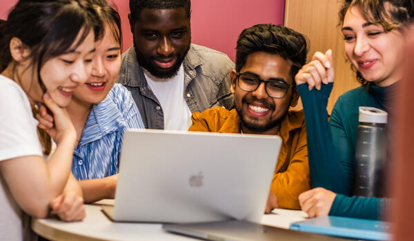 People from different ethnic groups looking at a laptop
