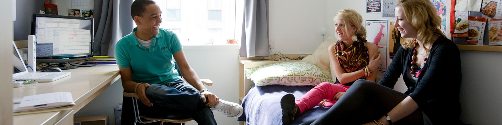 Three students sat outside campus accommodation laughing