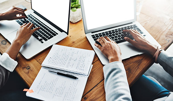 Two people working together on laptops