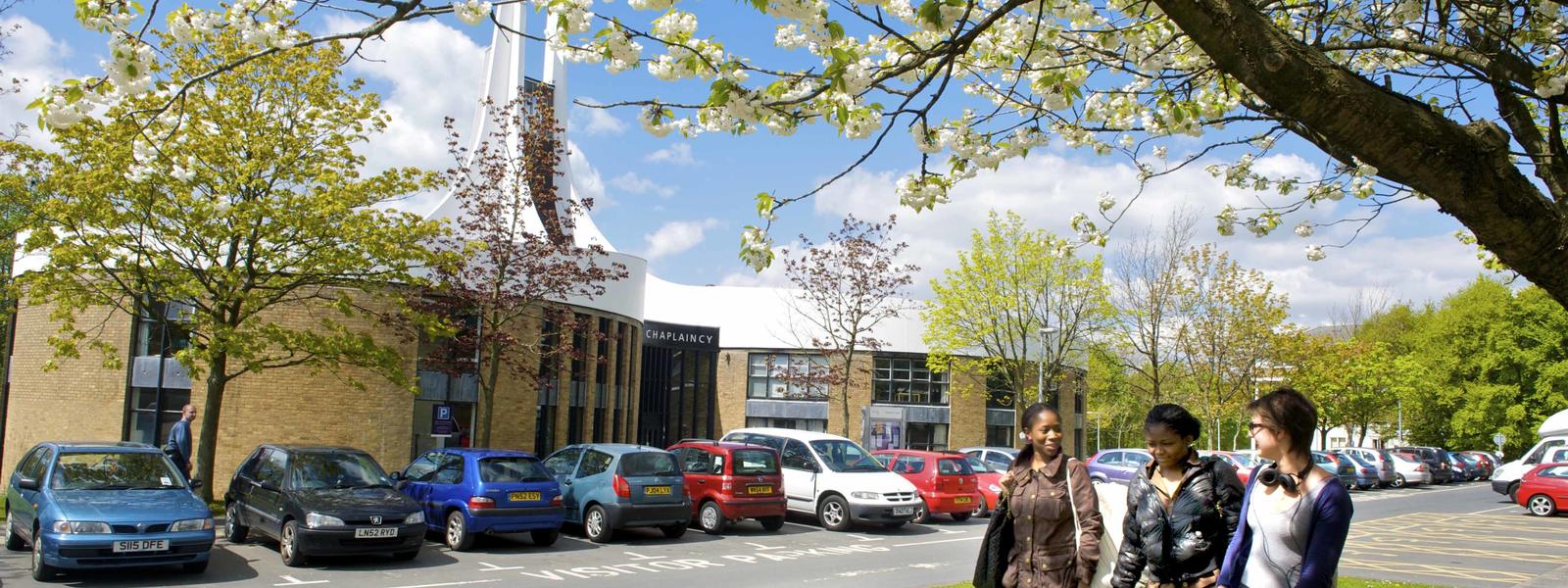 Three students walking outside Lancaster University's Chaplaincy Centre.