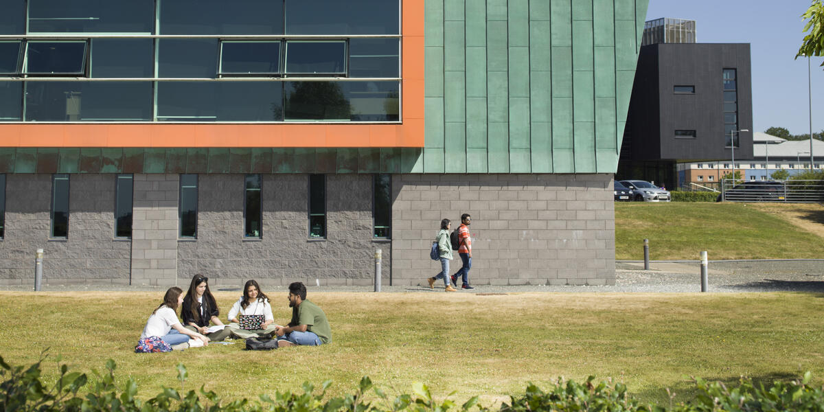 Students sat on the grass and walking outside of Infolab