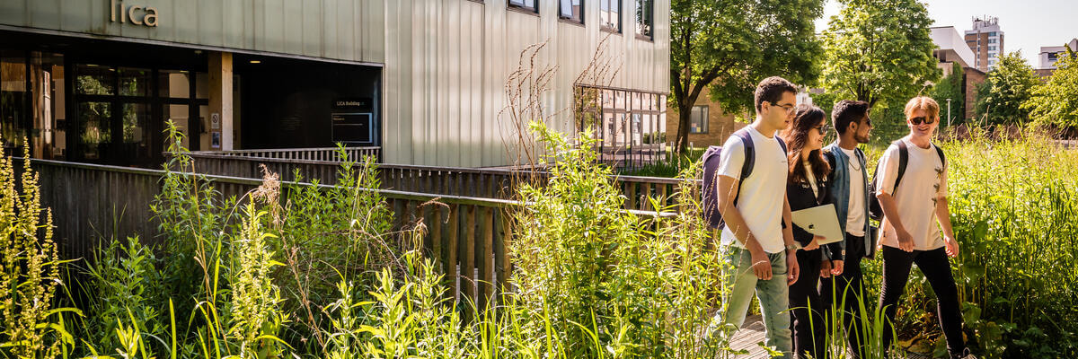 Students walking across a wooden bridge from the Lancaster Institute for the Contemporary Arts