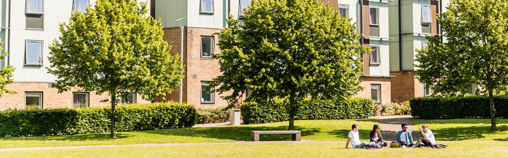 Students sat on grass outside of on-campus student accommodation