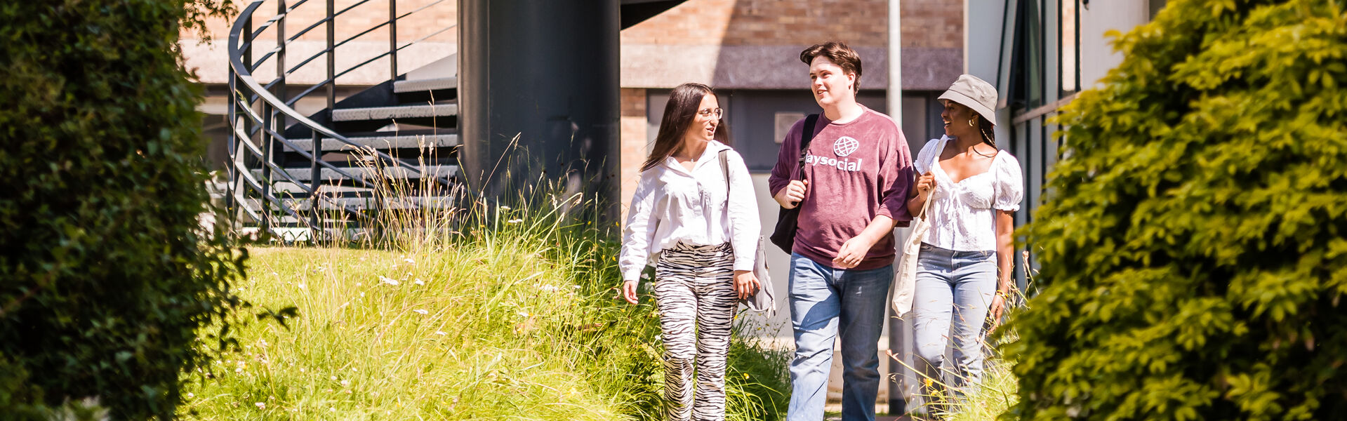 Three students walking and smiling together