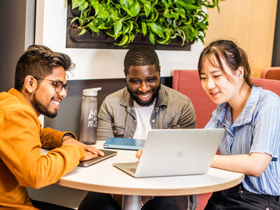 Three students looking at a laptop