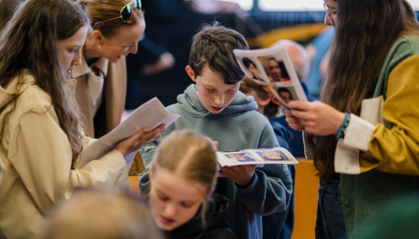 a group of people look at pieces of paper with face on them