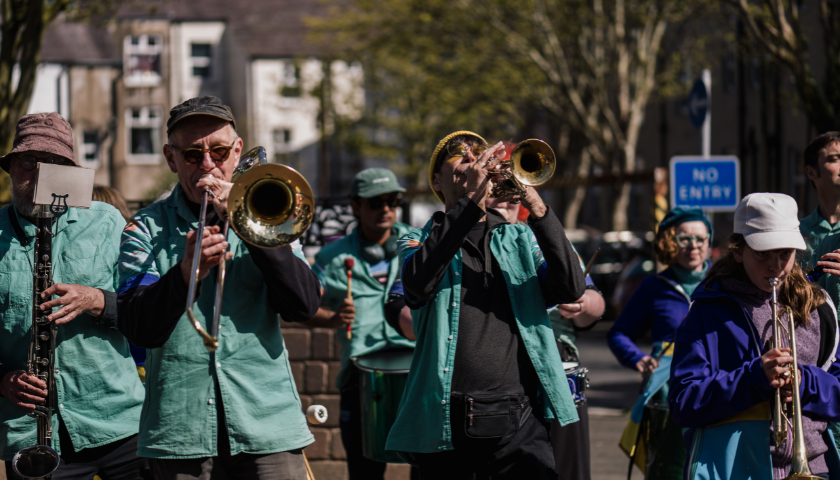 a band in turquoise shirts play brass instruments