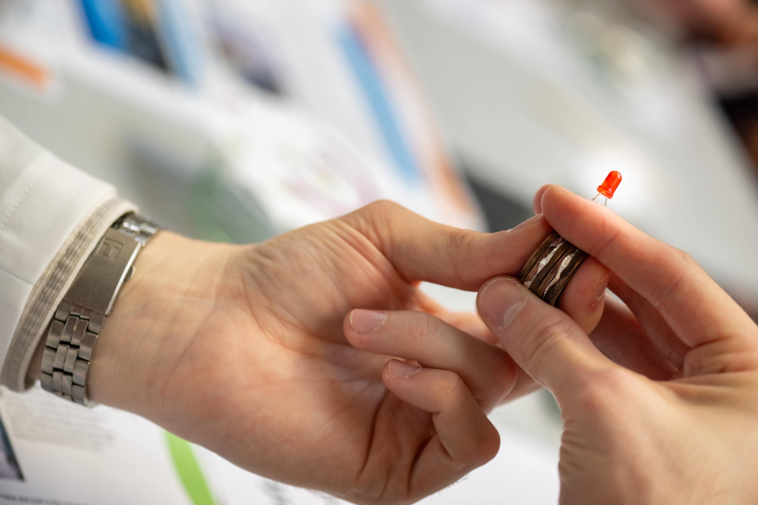 hands holding a stack of batteries lighting up a small red light