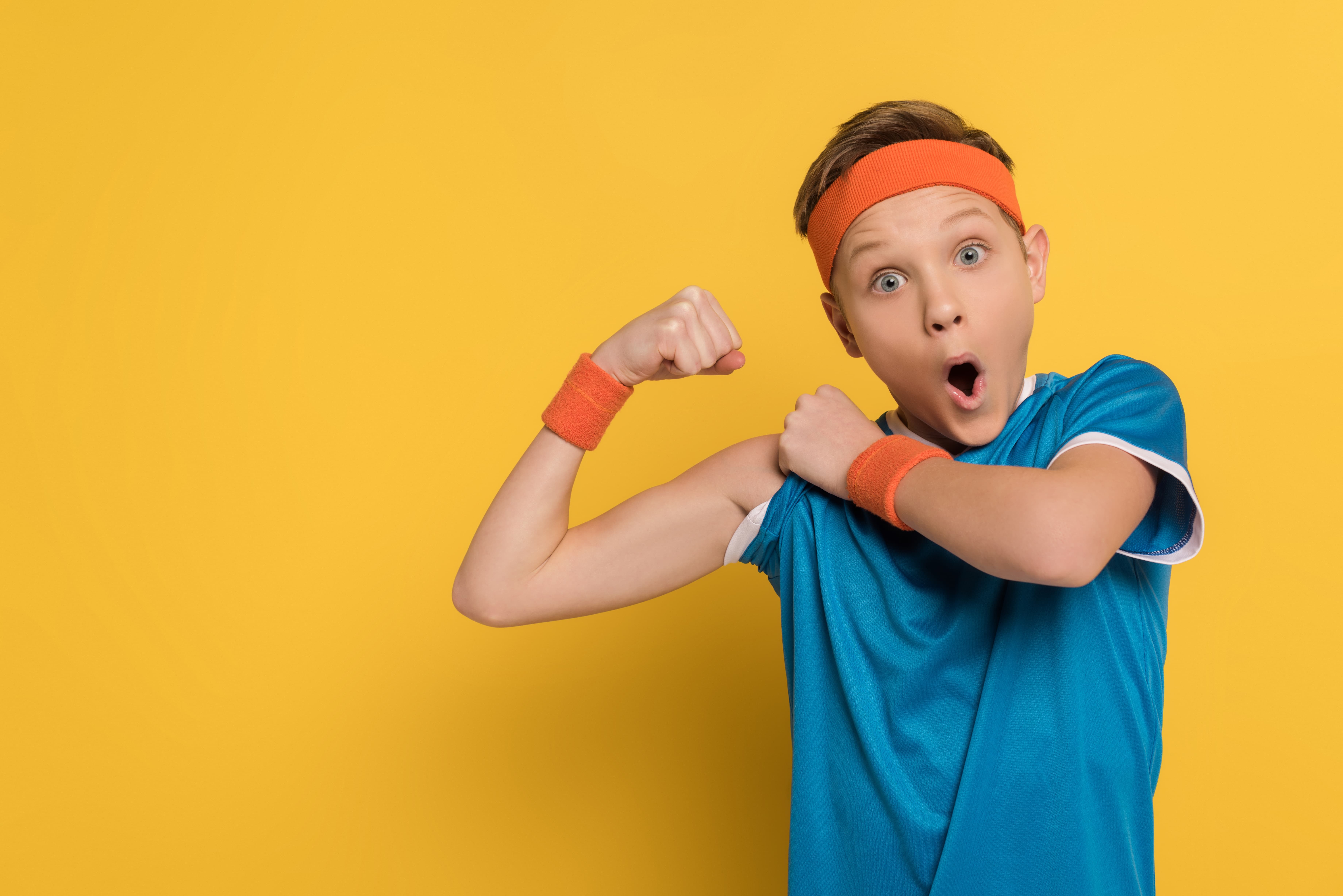 a boy in workout clothes shows off his arm muscles