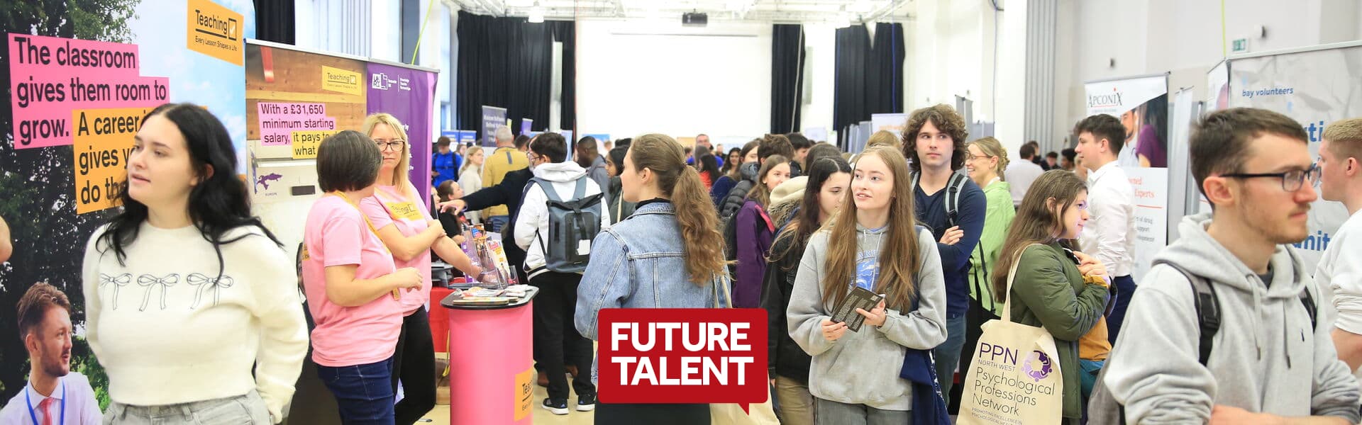 A busy indoor careers fair with students speaking to exhibitors