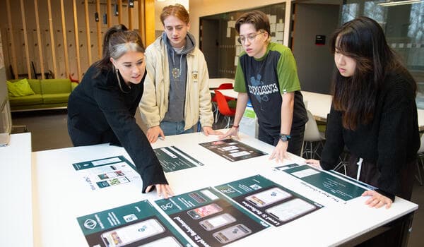 Four students reviewing design mockups on a table
