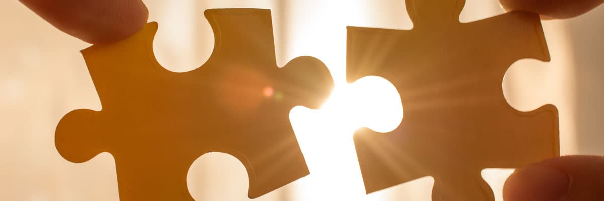 two hands trying to connect couple puzzle piece. with sunset background