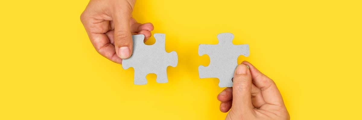 two hands trying to connect couple puzzle piece with yellow background
