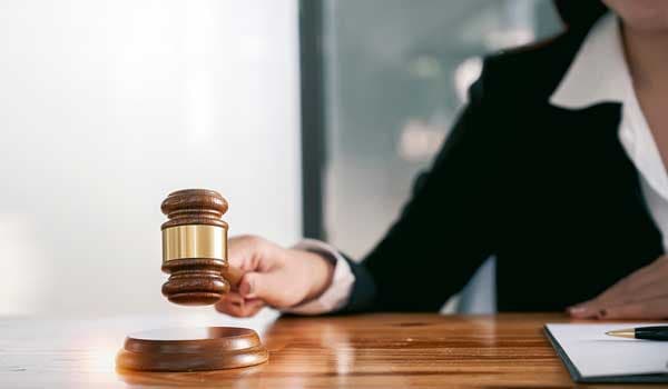 Woman judge hand holding gavel to bang on sounding block in the court room