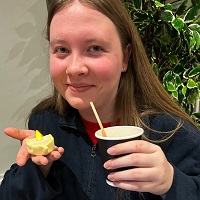 Close up of Amy Bellis holding a paper cup and straw in one hand and a tea light in the other.