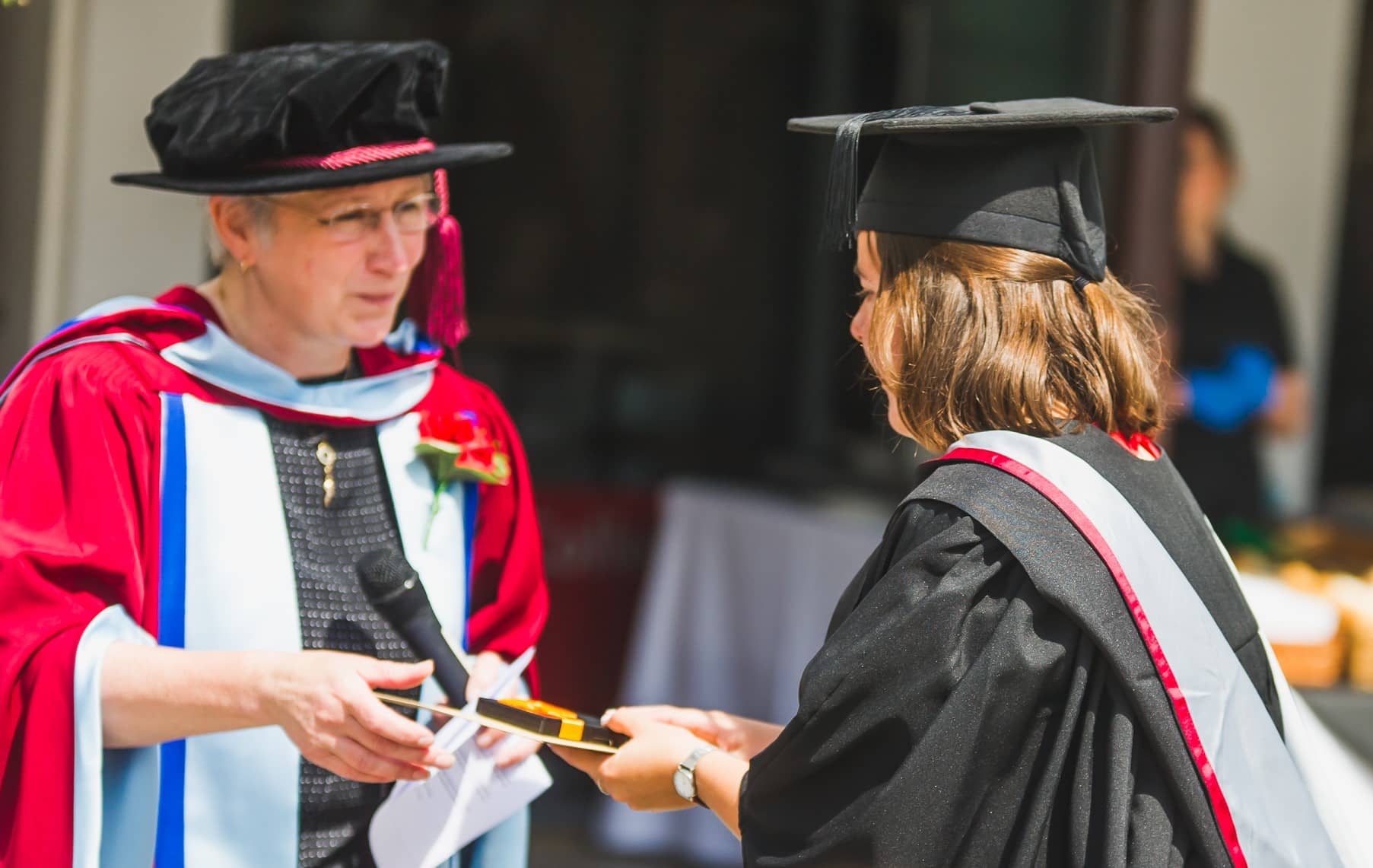Student receiving an envelope and gift from Dr Casey Cross