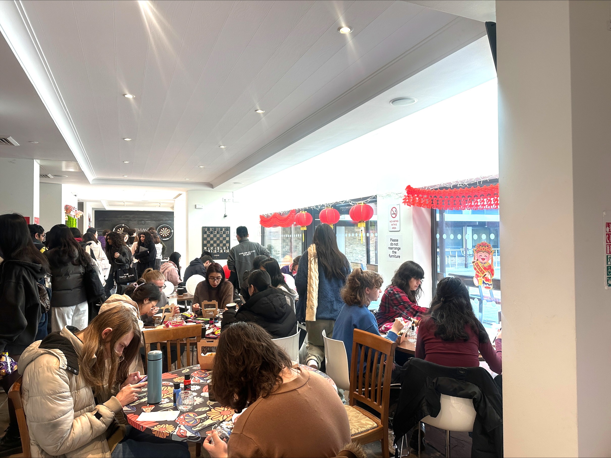 Tables filled with people sat crafting with other people standing by.