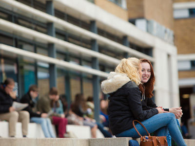 Two students sitting on steps smiling