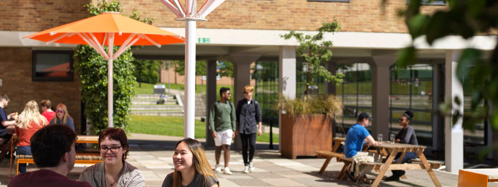 students sitting at picnic benches and walking through the common area