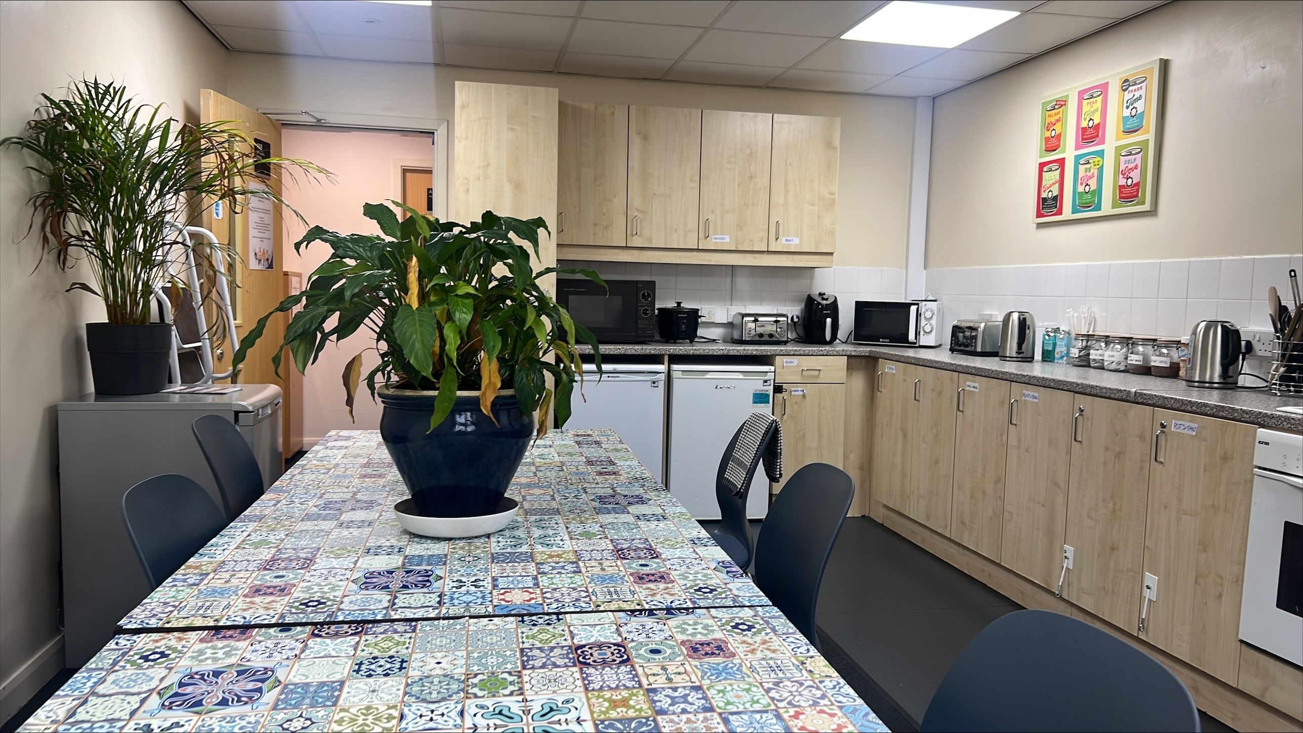 Kitchen with view of cupboards and dining table with plant on top.