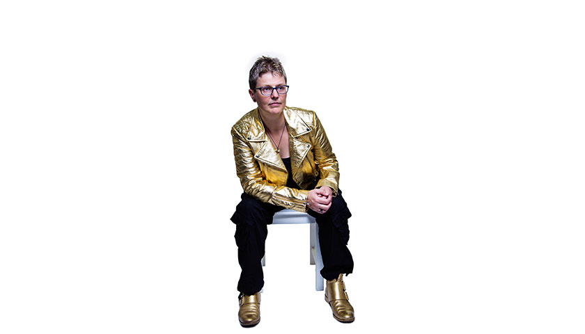 Dr Lucy Rogers sat on a chair wearing a gold jacket
