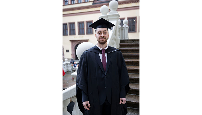 Ahmet Duser in their graduation cap and gown