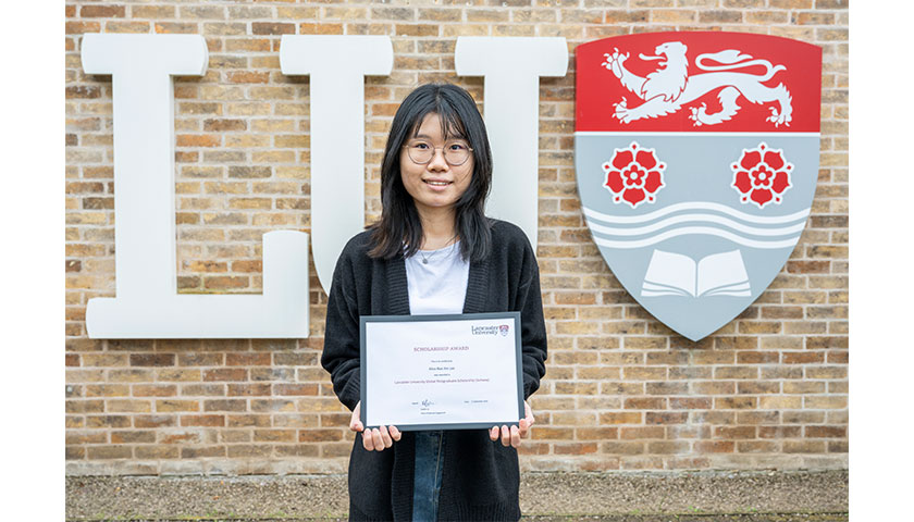 Alice Lee Nan Xin standing next to the LU Lancaster logo sign.