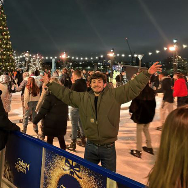 Student holding hands in the air and smiling on an ice rink