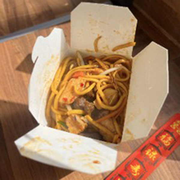 A box of hot chilli noodles with chopsticks on the side.