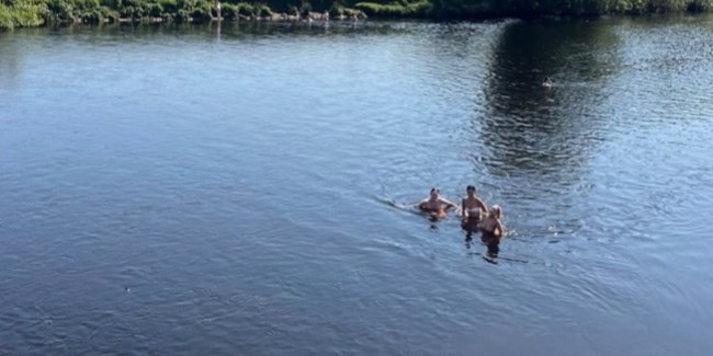 Three people in swimsuits enjoying the River Lune at Crook o' Lune on a sunny day.