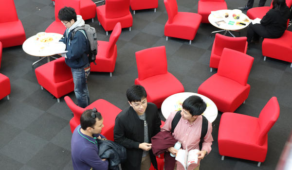 Students sitting on red chairs in the management school building