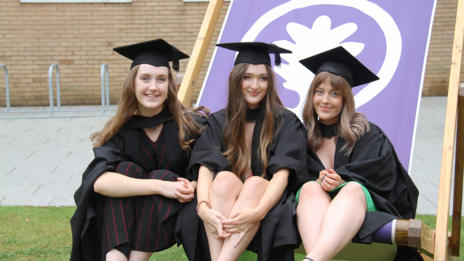 Catherine and two friends sit in a large, purple deckchair