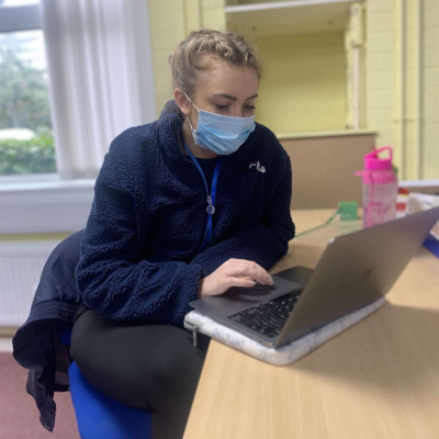 Digital content ambassador Kerrie using a laptop during a social work placement