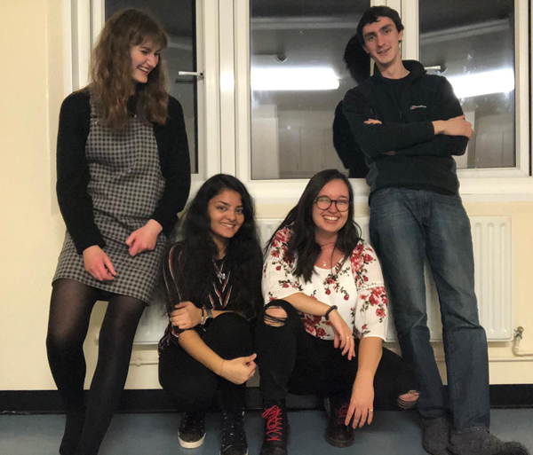 A group of three male and one female student, two standing and two kneeling