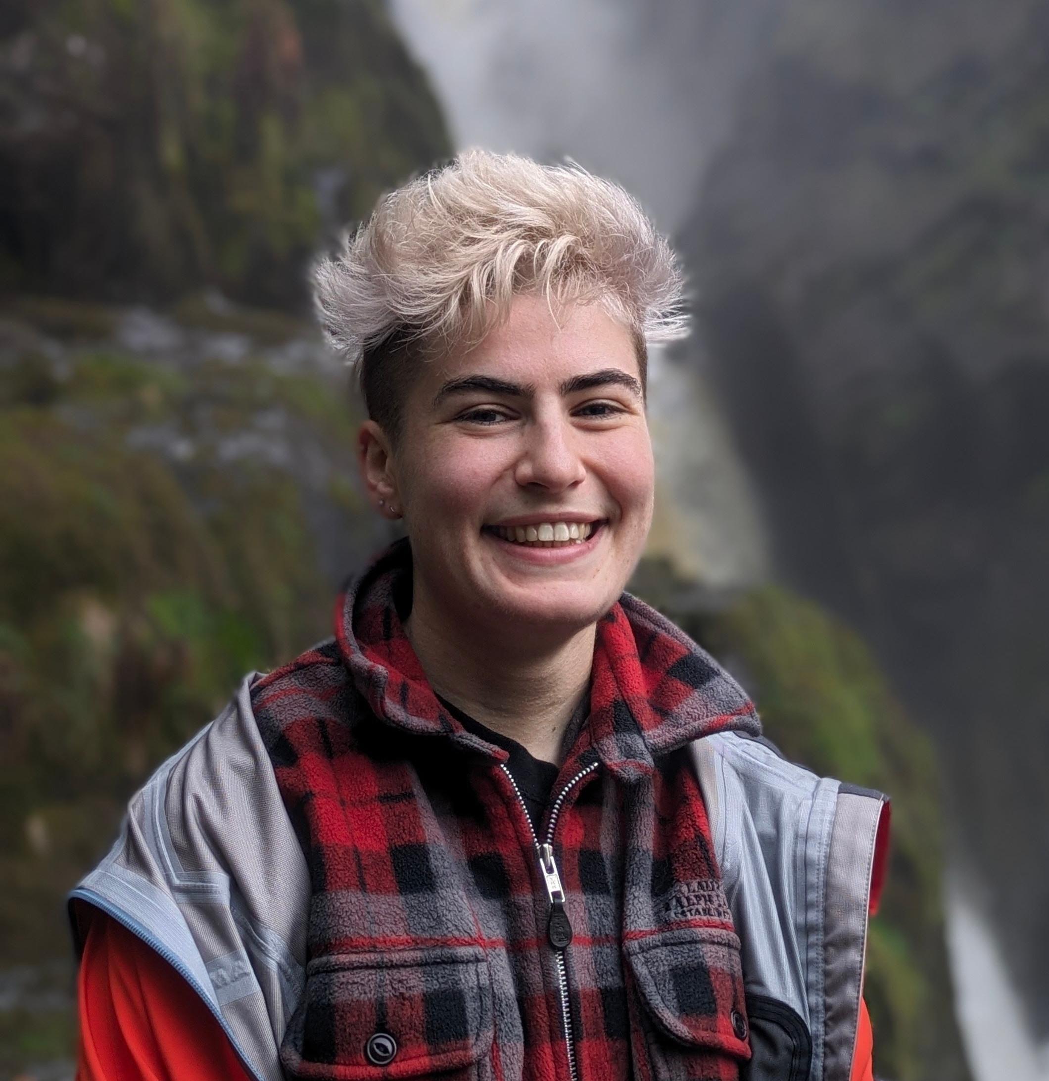 Panellist Ali Sheen stands in front of a waterfall.