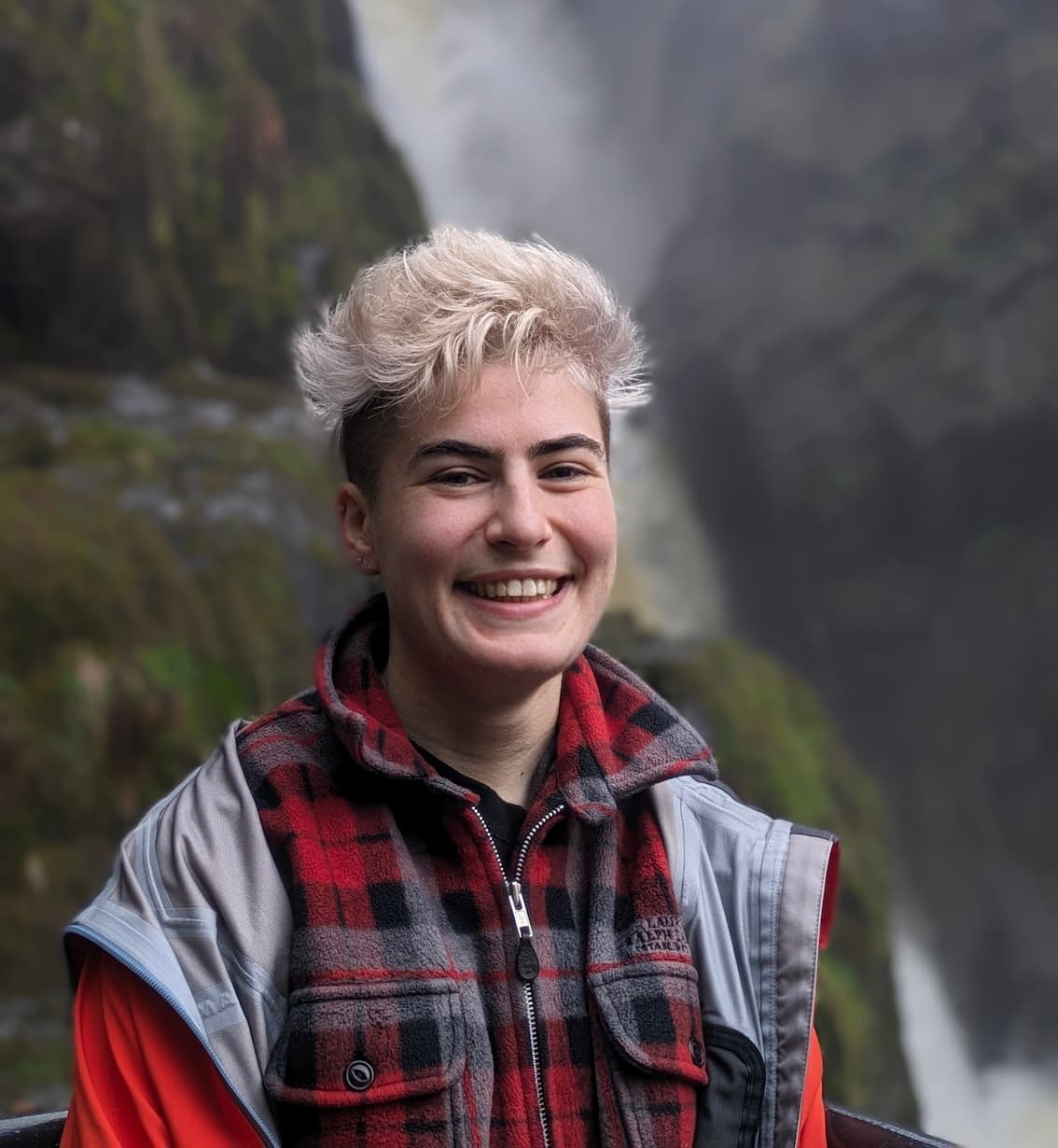 Panellist Ali Sheen stands in front of a waterfall.