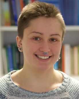 Alice is standing in a library in front of a shelf of books