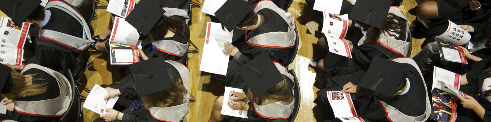 Seated graduates with programmes.